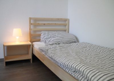 Monteurzimmer Einzelbetten mit Nachttisch und Lampe