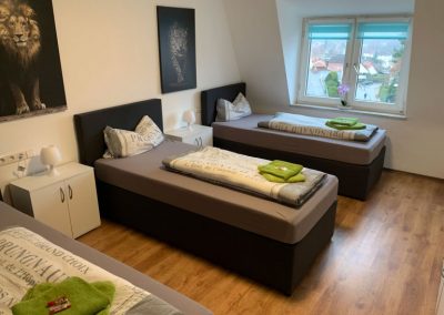 Monteurzimmer Einzelbetten mit Lampen und Tischen