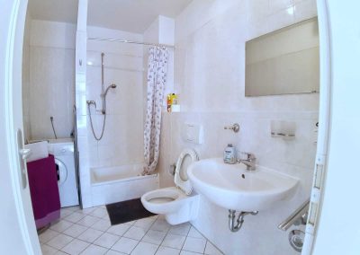 Monteurzimmer Badezimmer mit Waschbecken, Waschmaschine und Dusche