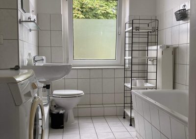 Monteurzimmer Badezimmer mit Waschmaschine, Wannendusche und Fenster